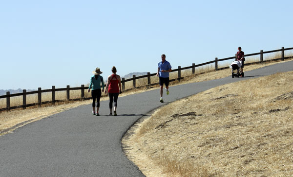 Two walkers and a runner enjoy a hike on the Dish hiking trail, named after the enormous antenna located nearby. (HAELIN CHO/The Stanford Daily)