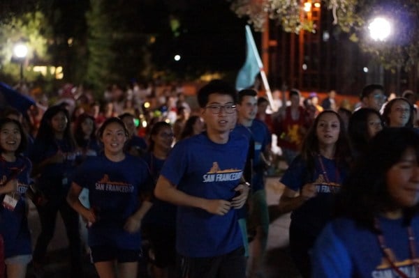 A group of students run outside at night as part of the Stanford tradition, Band Run.