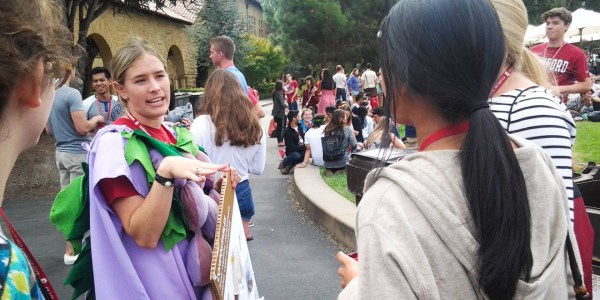 A staff member from the Office of Sustainability talks with students after they disposed of their lunch waste in the compost bins. Staffers dressed up in costumes and held signs to raise awareness about composting. (EMMA JOHANNINGSMEIER/The Stanford Daily)