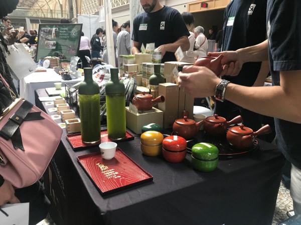 Matcha equipment laid out on a table with glasses and small tea cups.