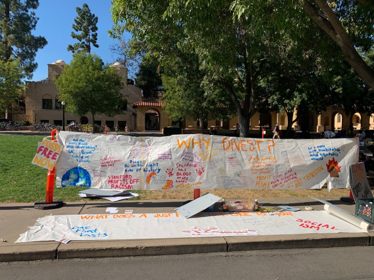 A sign hangs in white plaza calling for divestment.