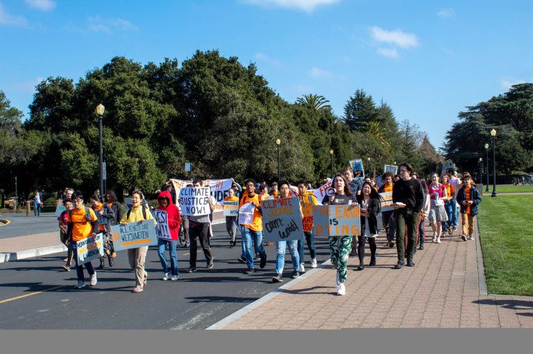 A large group of protestors walk in front of Main Quad