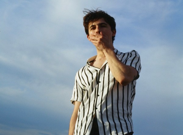 Tommy Florio stands against a cloud-streaked sky with his left hand over his mouth.