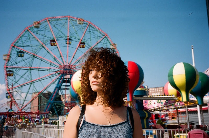 Loren Allred standing in front of a ferris wheel and other amusement rides