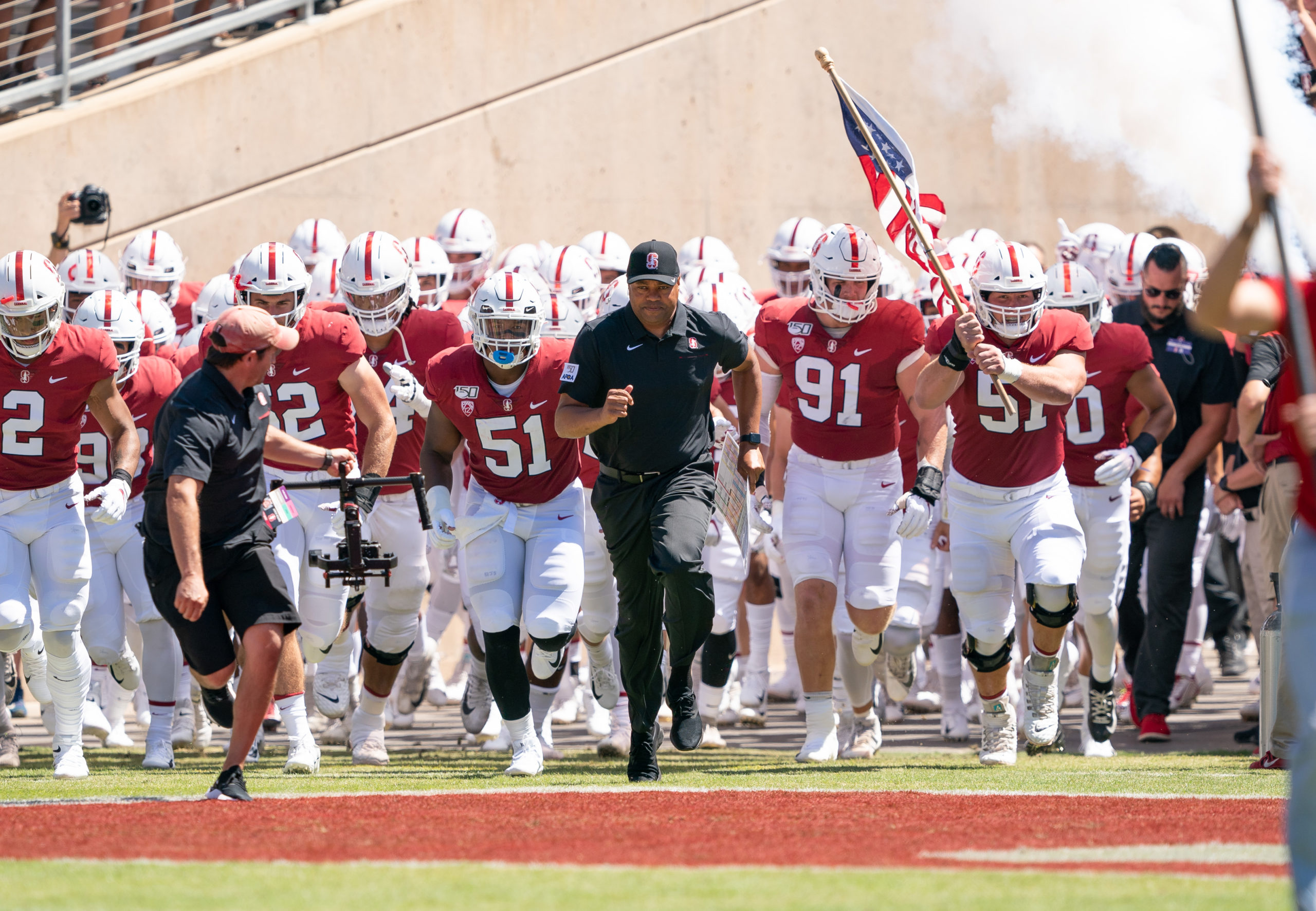 The Stanford football team runs out onto the field at the start of a game.