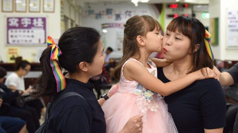 two women stand holding a little girl between them