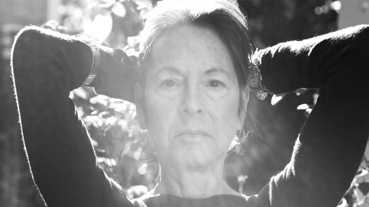 A black and white image of a woman (Louise Glück) posing with her hands behind her head.