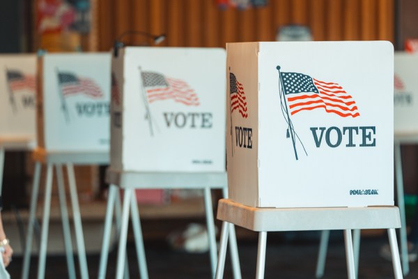 three cubicles with an American flag and "vote" on each wall of the cubicle shield