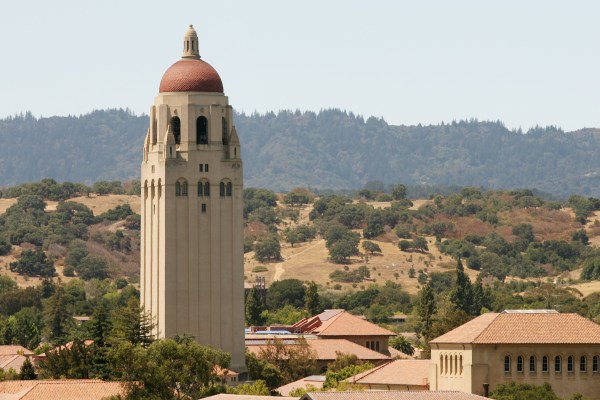 Hoover Tower above Stanford campus in front of green hills and grey sky.