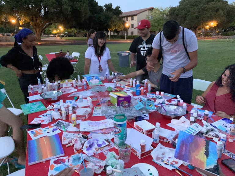 Students sit around a table doing art projects for SoCo.