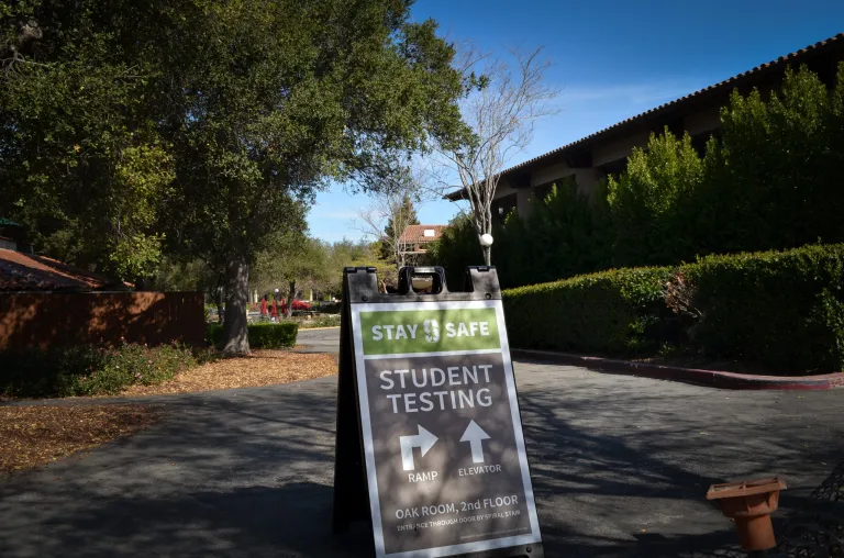 A sign on Stanford's campus with arrows points to locations of COVID-19 testing facilities