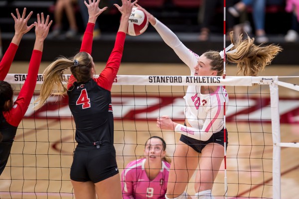 Kendall Kipp hits the ball over the net towards two defenders.