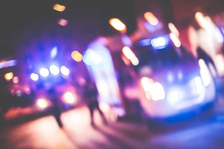 A blurred street with a vehicle and red and blue lights.