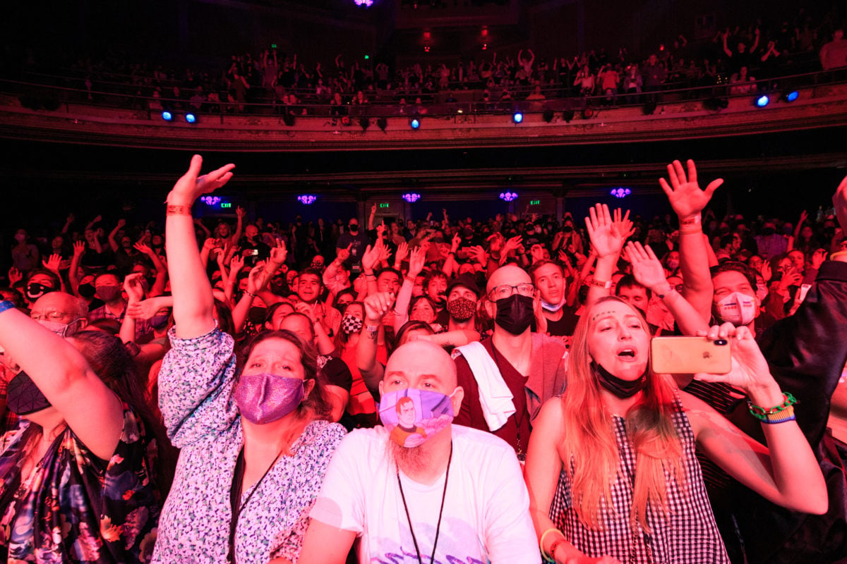 Wide image of the masked concert crowd illuminated red.