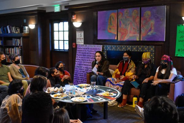 A group of masked people sit around a table.