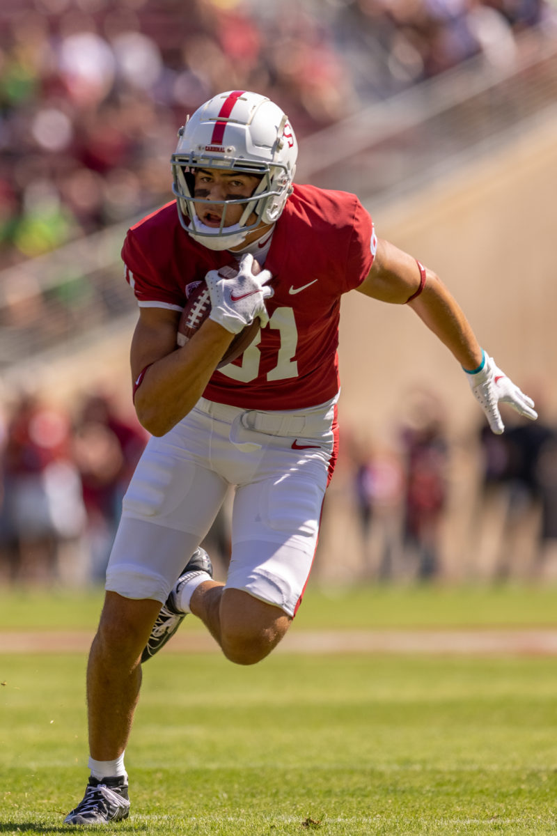 Brycen Tremayne runs on the field clutching the football in his right hand. 