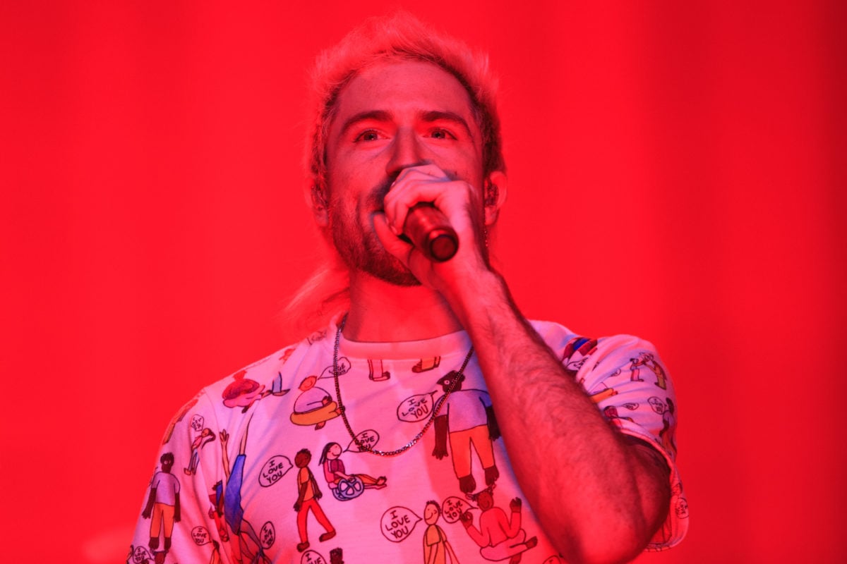 Close-up of Nicholas Petricca singing on a red-lit stage.