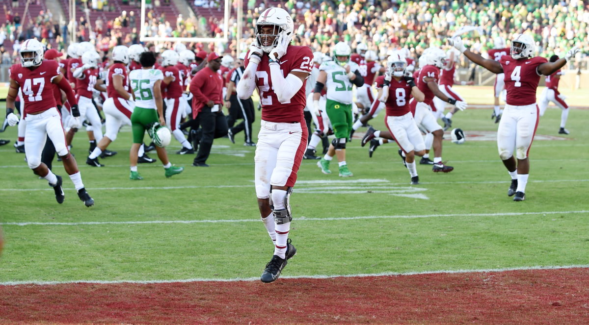 Junior cornerback Nicholas Toomer jumping up with both hands on his face in front of a crowd of both Cardinal and Ducks players.