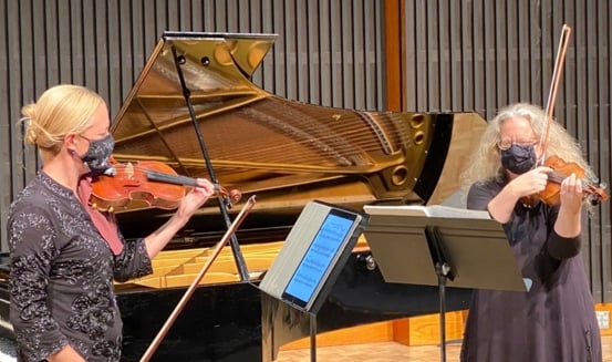 Two violinists playing together.