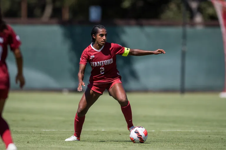 Senior defender Naomi Girma dribbles a soccer ball down a soccer field.