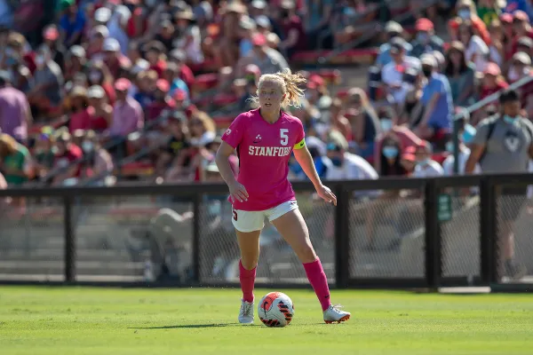 A woman dribbles a soccer ball up a soccer field.