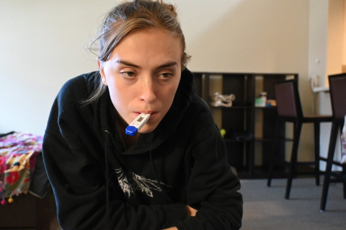 Anna McNulty poses for a self-portrait with a thermometer in her mouth.