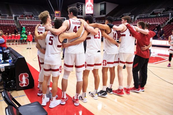 A group of seven basketball players face away from the camera with their arms around each other after the game has ended.