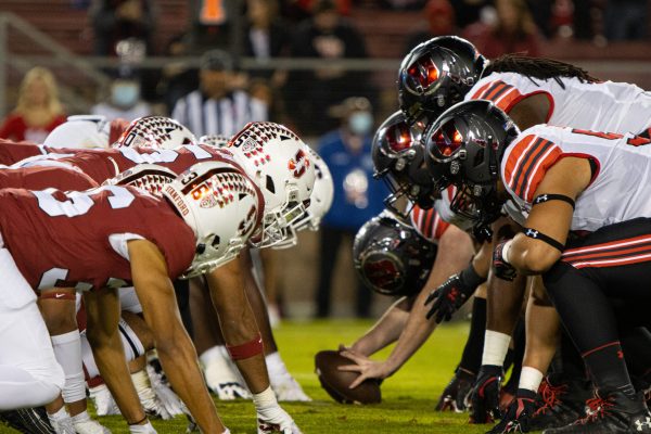 Two teams of players line up on either side of a football on the grass.