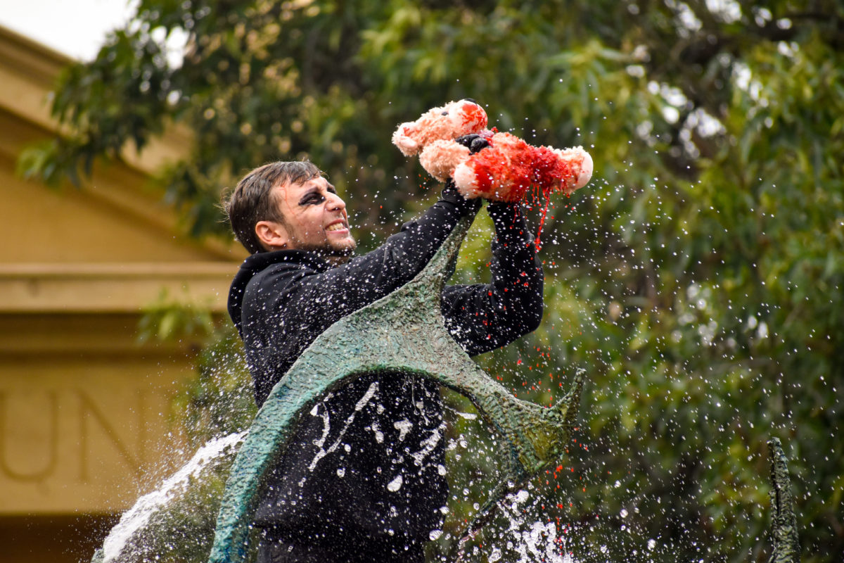 A band member, dressed in all black, stabs a bleeding teddy bear on the top of The Claw.