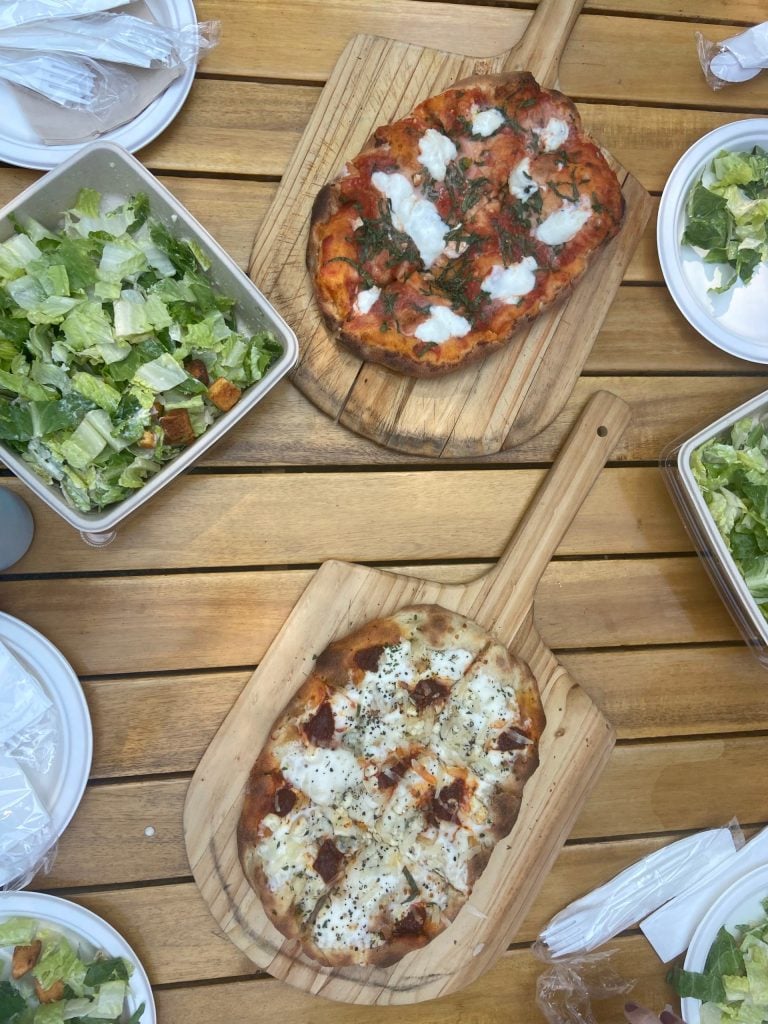 An assortment of pinsas and salad on a wooden table at Treehouse