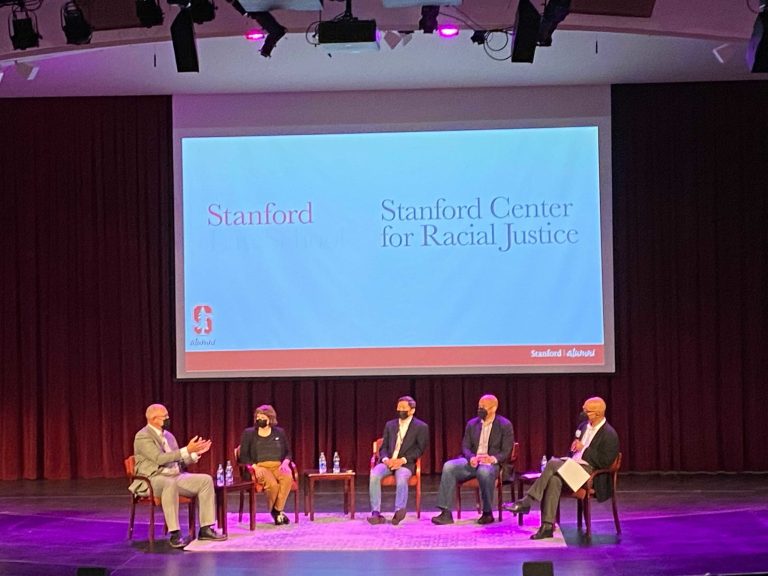 Five people including Senator Cory Booker sit on stage at a panel event.