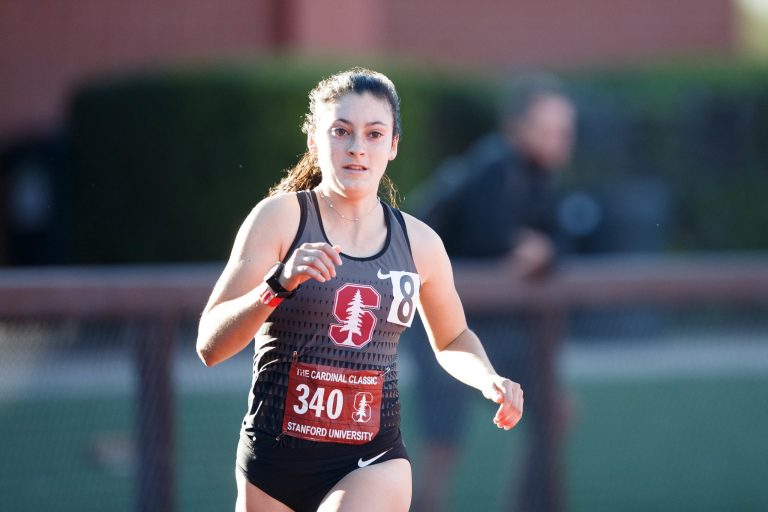 A woman runs on the track in a Stanford jersey.