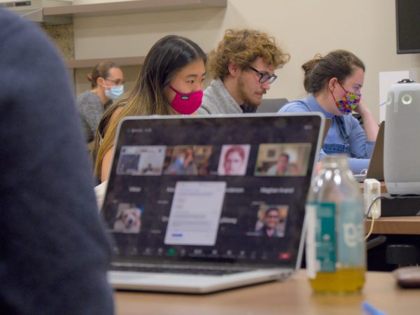 Computer and three graduate student councilors sitting at a table