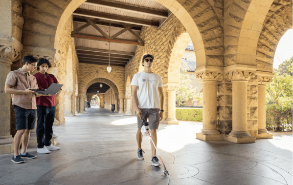 Person holding a cane and stepping forward in a hallway near the Main Quad.