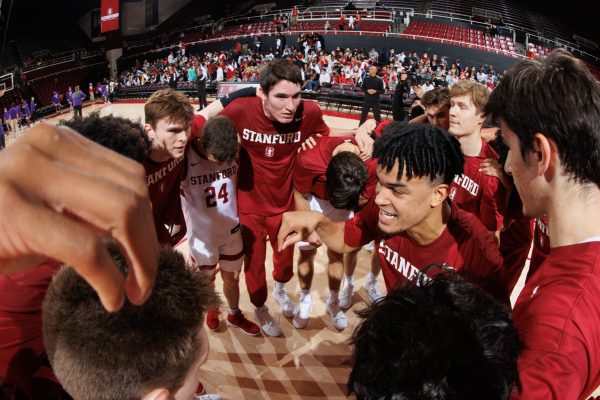 Stanford men's basketball huddles alongside the court.