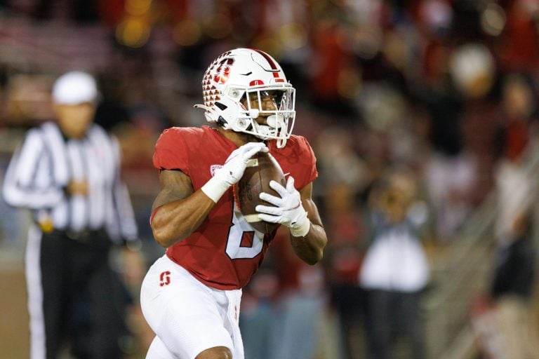 A football player carries a football as he looks downfield to throw a pass.