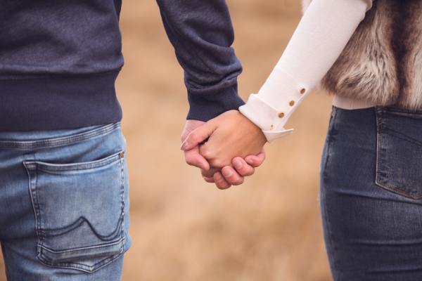 two people holding hands in a field of grass