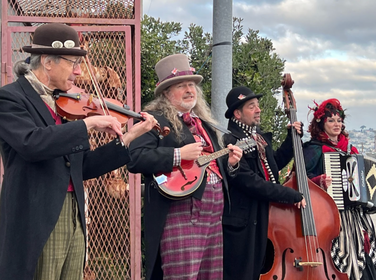 Four Dickens' characters lined up playing musical instruments.