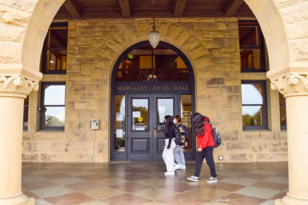 Masked students walk in front of Building 460, Margaret Jacks Hall