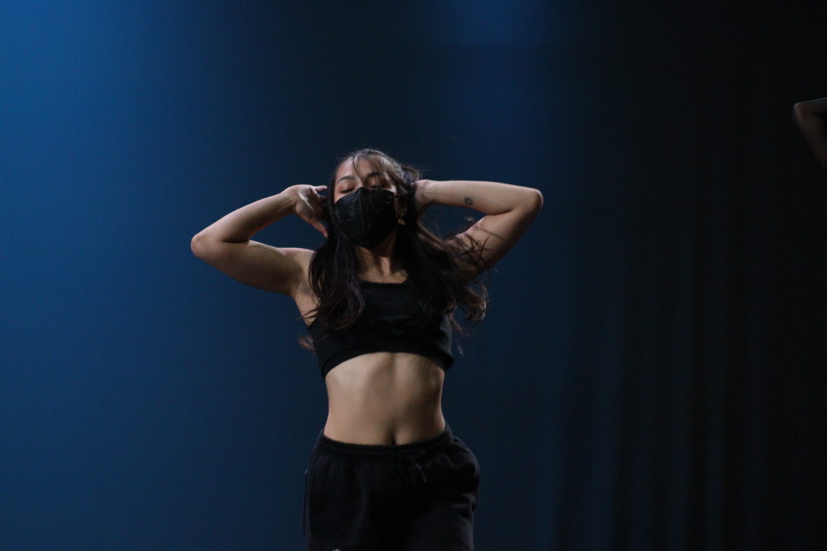 A solo dancer framed in the center, wearing all black.