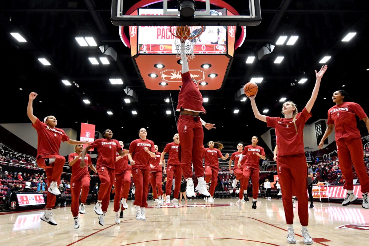 Fran Belibi dunks before one of the women's basketball team's games with the rest of her teammates looking on.