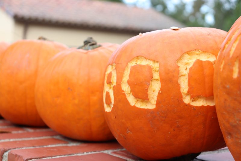 Four pumpkins. The closest one has the word "BOO" carved in it.