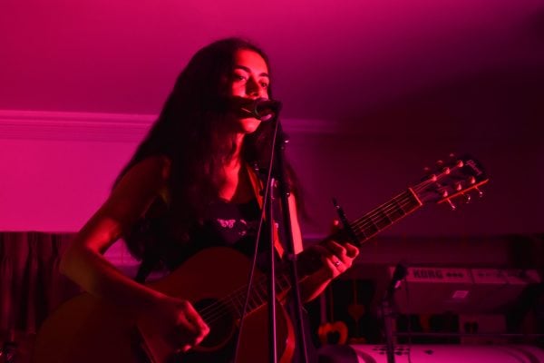 Woman plays guitar and sings with pink lighting