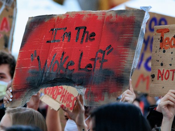 Protester holding a sign saying "I'm the 'Woke Left'"