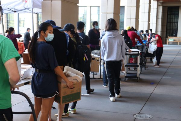 The line grows longer as more students join with their bags and boxes to carry their food.