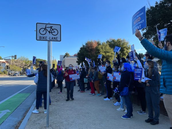 A group of demonstrators at a rally hold signs that read 'CRONA nurses need a fair contract NOW!'