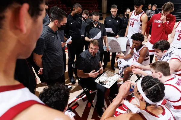 Jerod Haase speaks to the men's basketball team as the players huddle around him.