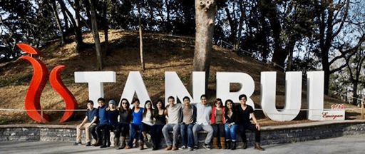 A group of students sit together on a bench in front of a large sign that says "Istanbul."