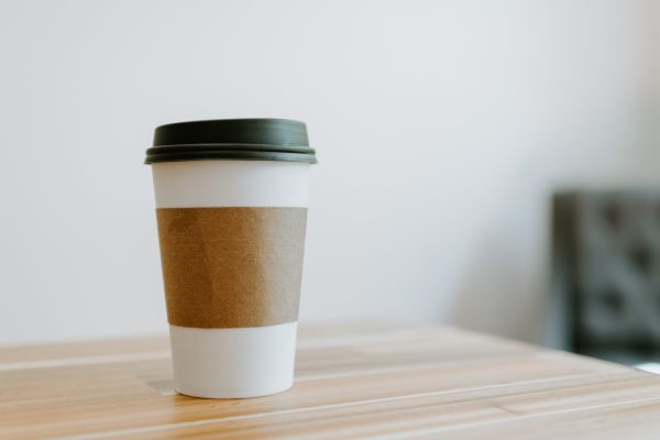 A close-up of a to-go cup of coffee on a wooden table/