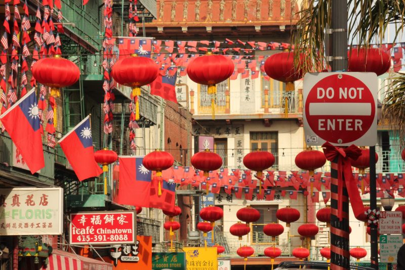 A collection of red lanterns and Taiwanese flags between several buildings. A "Do Not Enter" sign stands to the right.